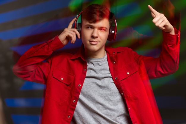 Jonge man in rood shirt met koptelefoon luisteren naar muziek