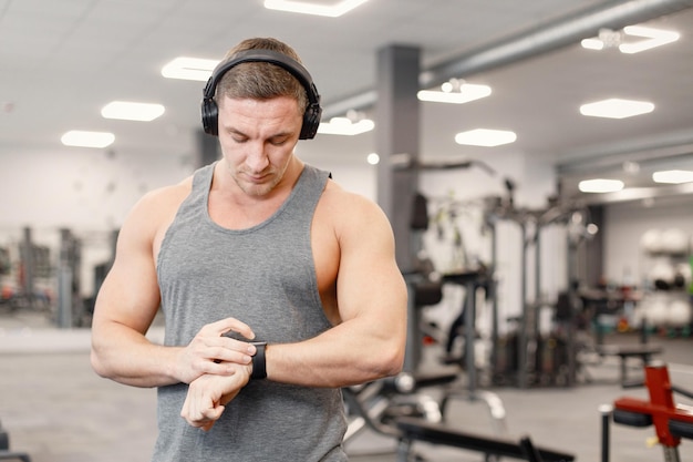 Jonge man in sportkleding kijken op sportwatch op sportschool