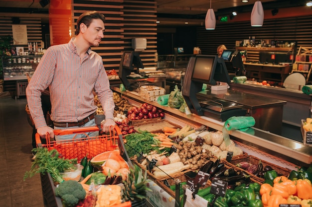 Jonge man in supermarkt duwen grafiek