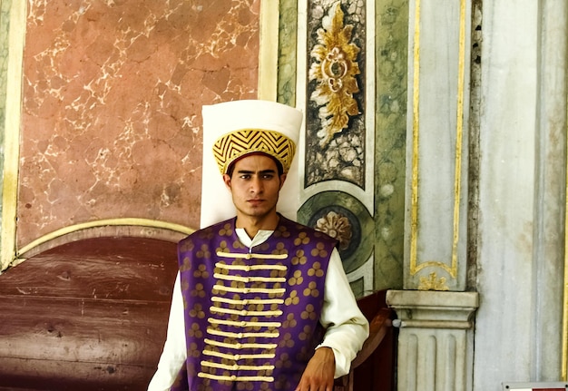 Foto jonge man in uniform die tegen de muur staat.