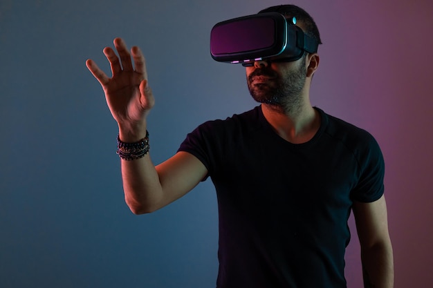 Jonge man in vr-bril headset interactie met virtual reality in kleur neonlicht toekomstige technologie...