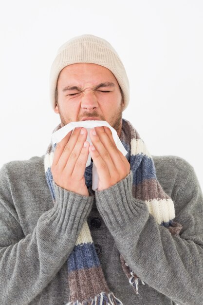 Jonge man in warme kleding niezen