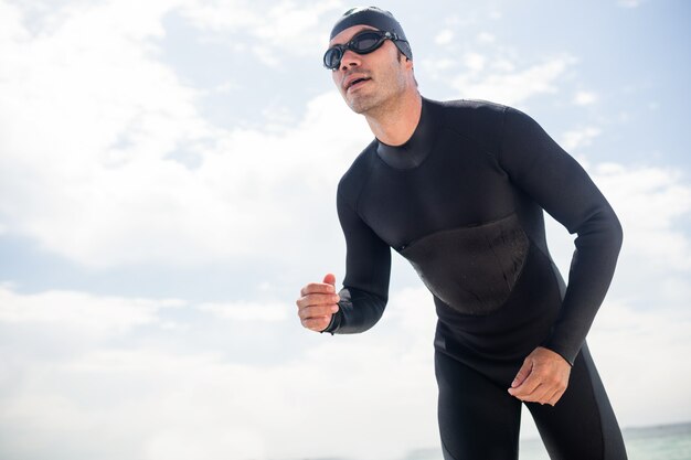 Jonge man in wetsuit klaar om op strand te lopen