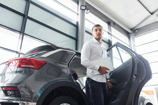 Jonge man in wit overhemd is binnen met moderne nieuwe auto