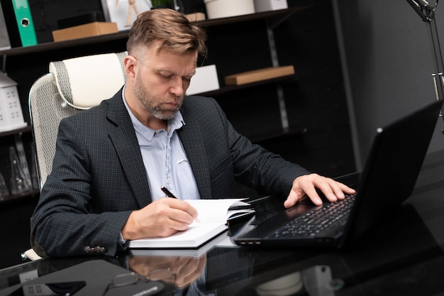 Foto jonge man in zakelijke kleding werken met laptop en agenda