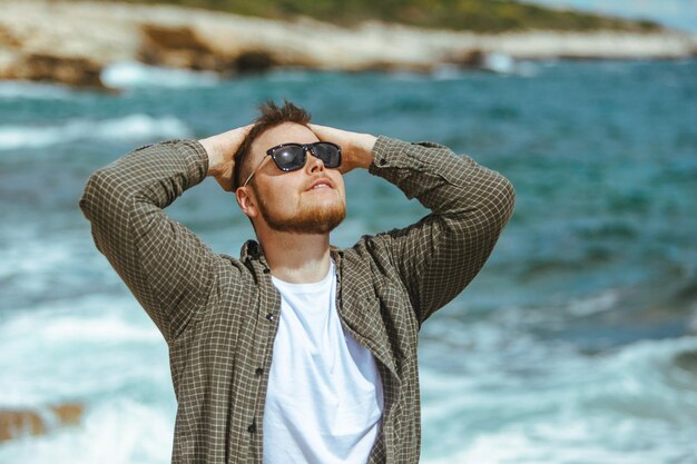 Jonge man in zonnebril met baard portret op zomervakantie aan zee