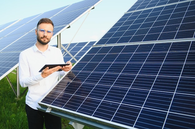 Jonge man ingenieur in wit overhemd met een tablet en het verifiëren van de fotovoltaïsche panelen op de zonne-energiecentrale Kopieer ruimte voor uw tekst