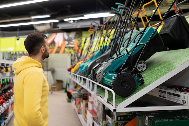 Jonge man kiest een elektrische grasmaaier voor zijn gazon