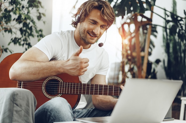 Jonge man kijken gitaar tutorial op zijn laptop