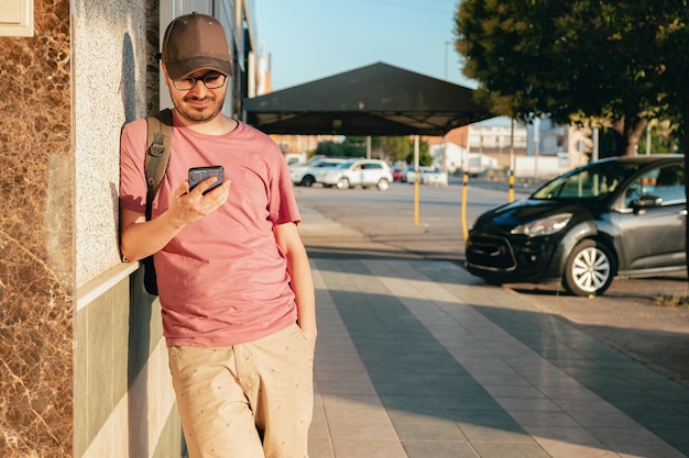 Jonge man kijkt naar zijn mobiele telefoon terwijl hij op straat staat