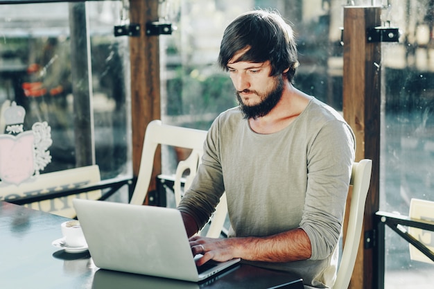 Jonge man koffie drinken en het gebruik van laptop in terras