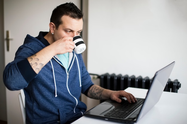 Jonge man koffie drinken en werken