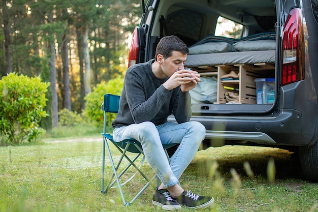 Jonge man koffie drinken naast zijn camper Ontspan tijd in de natuur