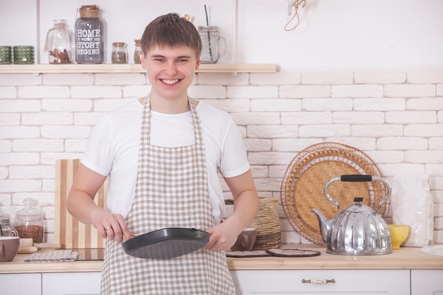 Jonge man koken. Aantrekkelijk mannetje bij de keuken die diner of ontbijt voorbereidt. Chef op de keuken.