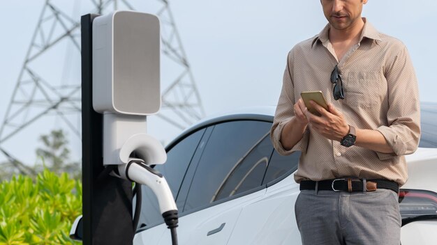 Jonge man laadt de batterij van een elektrische auto op bij een laadstation