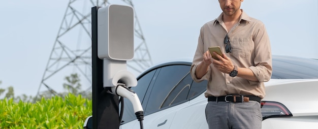 Jonge man laadt de batterij van een elektrische auto op bij een laadstation