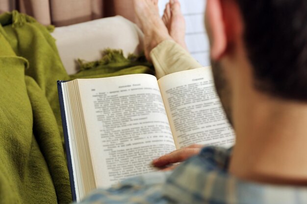 Jonge man leesboek op sofa close-up