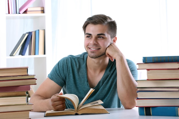 Jonge man leest boek aan tafel in de kamer