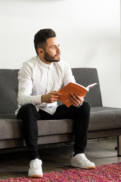 Jonge man leest een boek op zijn bank Netwerkmarketingmedewerker