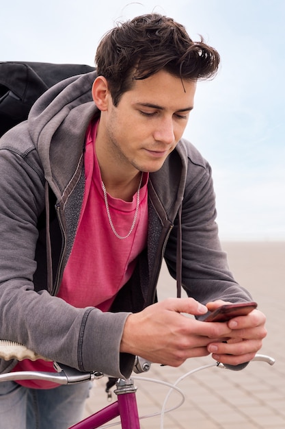 Jonge man leunend op een fiets met behulp van slimme telefoon