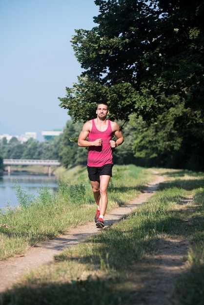 Jonge man loopt in bebost bosgebied - training en oefenen voor trailrun marathon uithoudingsvermogen - fitness gezonde levensstijl concept