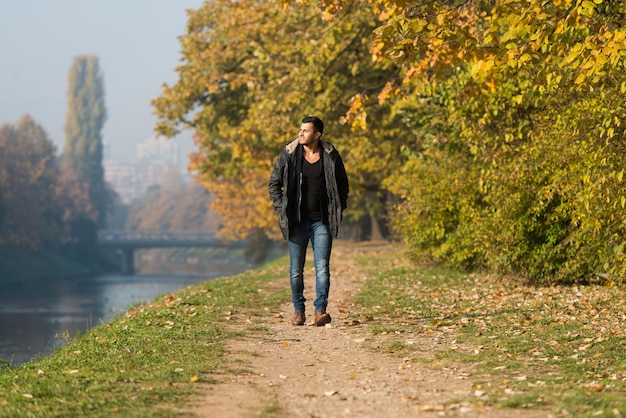 Foto jonge man loopt in het bos door het bos buiten in de herfst