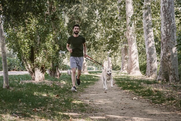 Jonge man loopt naast zijn hond labrador in een stadspark