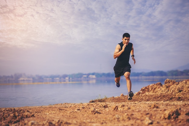 Jonge man loper loopt parcours op zonsopgang aan het meer gezond en lifestyle concept