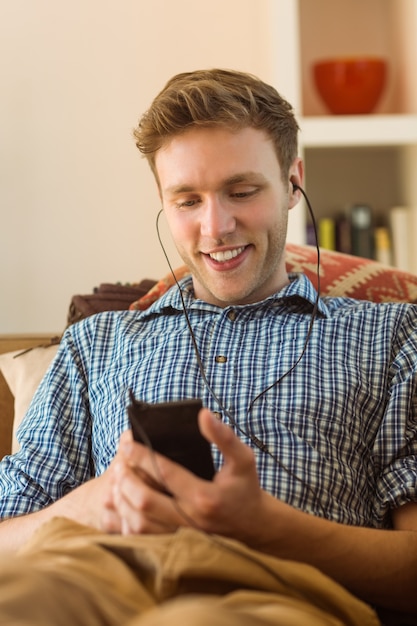 Foto jonge man luisteren naar muziek op zijn bank