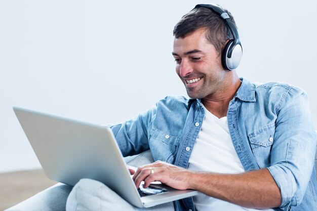 Jonge man luisteren naar muziek tijdens het gebruik van laptop