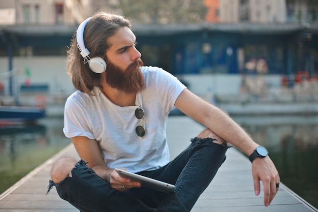 jonge man luistert naar muziek aan het meer