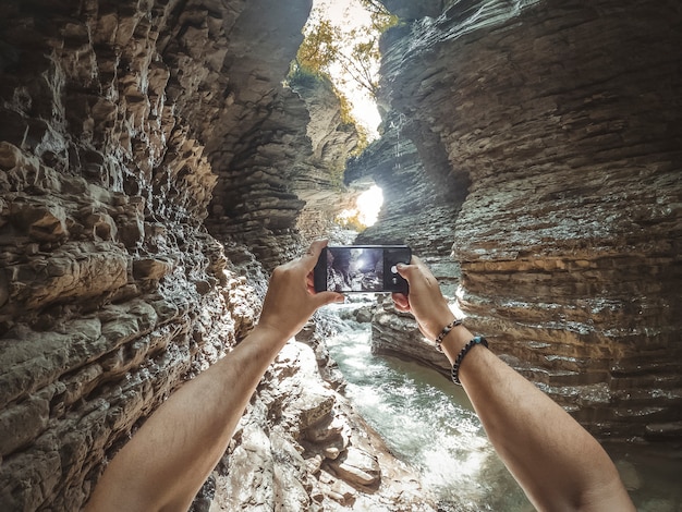 Jonge man maakt een foto met zijn mobiele telefoon in de canyon.