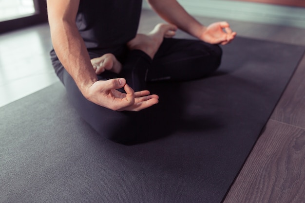 Jonge man mediteert tijdens het beoefenen van yoga in lotushouding