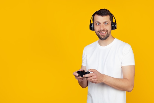 Jonge man met baard in wit t-shirt gamer spelen van videospellen met koptelefoon glimlachen