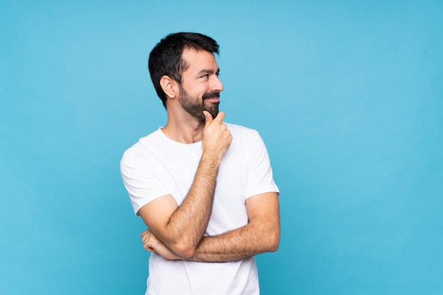 Jonge man met baard over blauw op zoek naar de kant