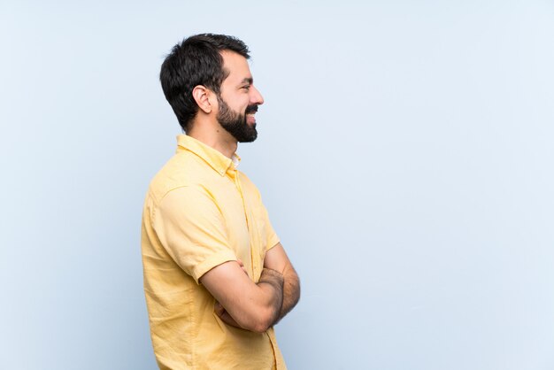 Jonge man met baard over geïsoleerde blauw in zijpositie