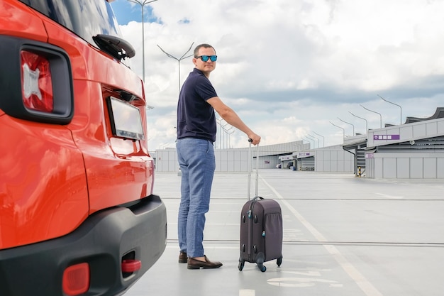 Jonge man met bagage in het concept van de zakenreis van de luchthavenparkeerplaats