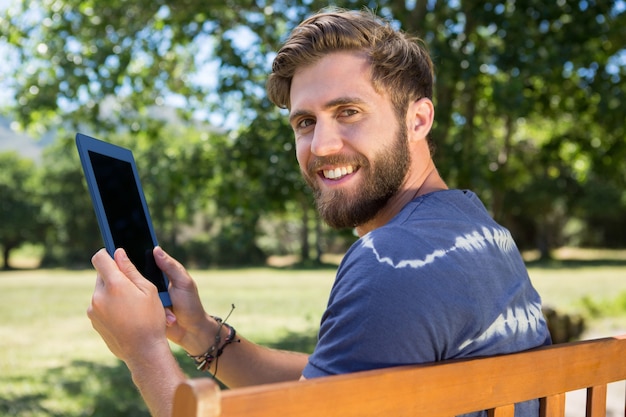 Jonge man met behulp van de tablet op een bankje