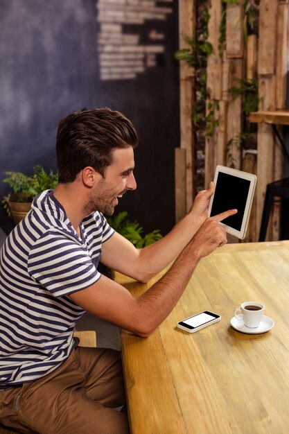 Jonge man met behulp van digitale tablet in cafetaria