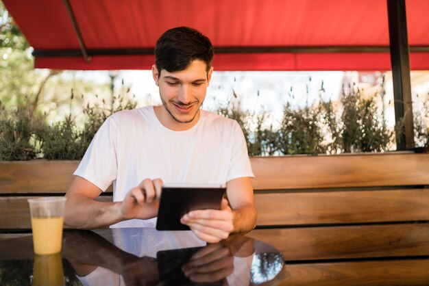 Jonge man met behulp van een digitale tablet bij coffeeshop.