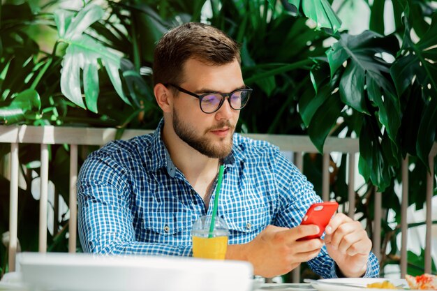 Jonge man met behulp van mobiele telefoon in een café