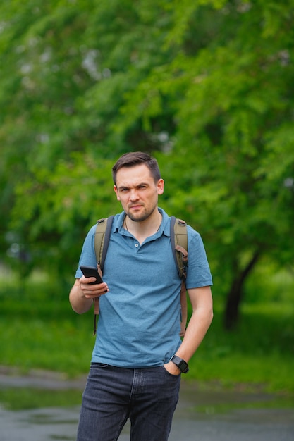 Jonge man met behulp van mobiele telefoon in het bos tijdens het wandelen