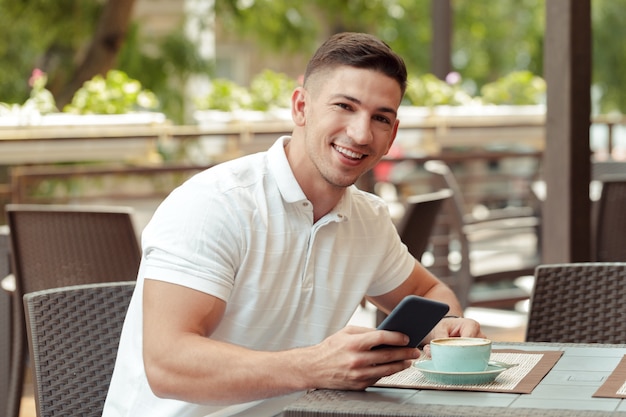 Jonge man met behulp van smartphone in café