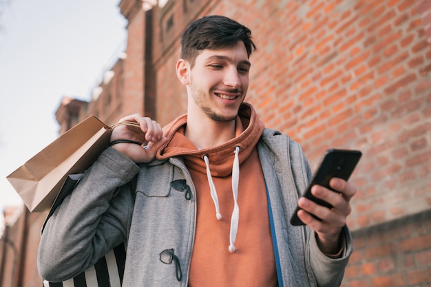 Jonge man met behulp van zijn mobiele telefoon op straat.