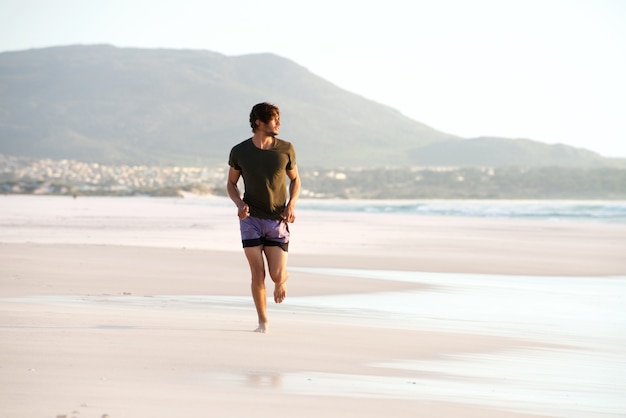 Jonge man met blote voeten op het strand