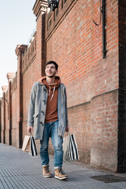 Jonge man met boodschappentassen tijdens het wandelen op straat.