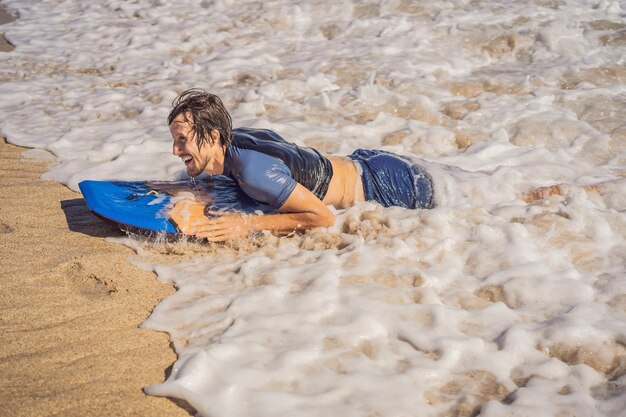 Jonge man met boogieboard op het strand