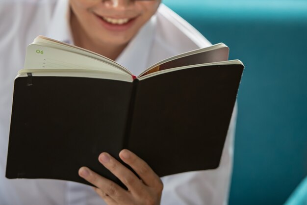 Jonge man met bril lezen van een boek op de bank.