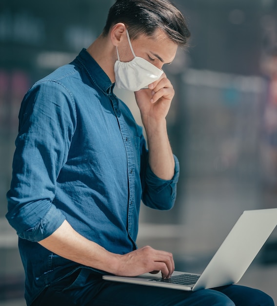 Jonge man met een beschermend masker praten op een smartphone.