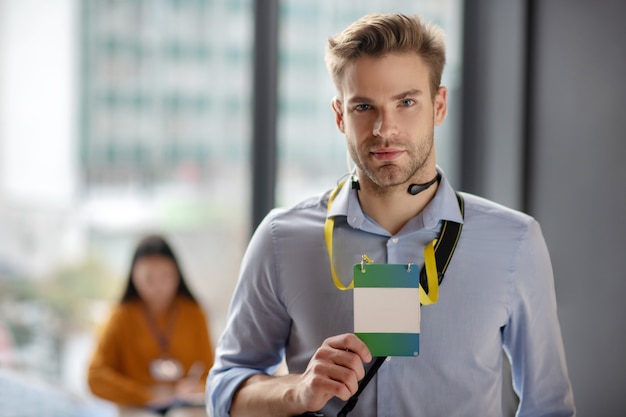 Jonge man met een blauw shirt met zijn badge